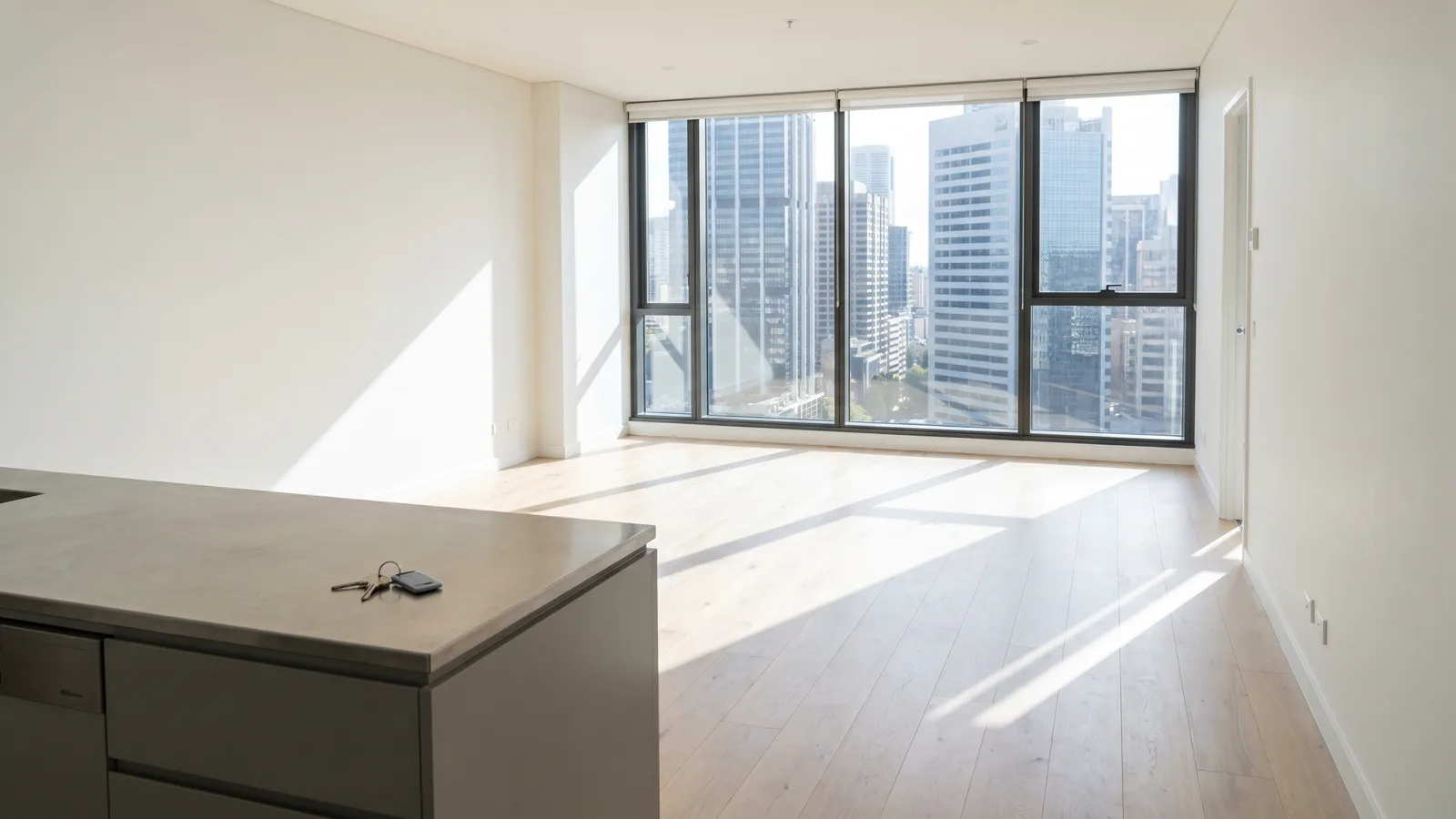 An emptied Sydney apartment in morning light, keys left on the kitchen bench, city towers through the window